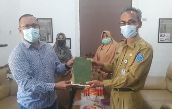 Erwin Djali menyerahkan buku tua kepada Kepala DKPUS Babel Asyraf Suryadin, Selasa (25/5/2021). 