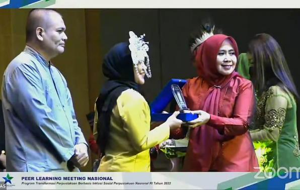 Kepala DKPUS Babel Rakhmadi diwakili Pustakawan DKPUS Babel Cahya saat menerima penghargaan dari Perpusnas RI di malam penutupan PLM 2022 di Surabaya. 