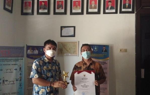 Kepala DKPUS Babel Rakhmadi menyerahkan Tropi Lomba 13 besar Perpustakaan SLTA Tingkat Nasional tahun 2021 kepada Kepala SMAN 1 Puding Besar, Kamis (14/10/2021).