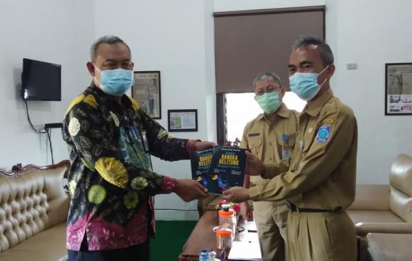 Kepala DKPUS Babel Asyraf Suryadin didampingi Pustakawan Ahli Madya DKPUS Babel Padli menyerahkan Buku Sejarah Bangka Belitung menjadi Provinsi kepada Kepala Dinas Perpustakaan dan Kearsipan Belitung, Paryanta.