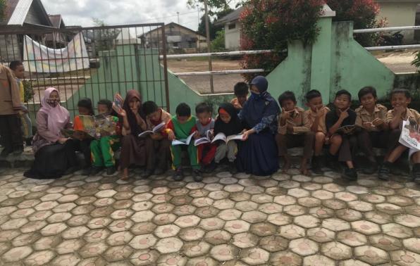 Walaupun membaca sambil duduk di pinggir pagar, namun anak-anak SDN 1 Payung ini tetap semangat.